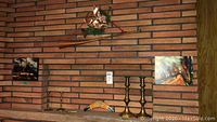 Shelf and wall display showing two pairs of brass candlestick holders (two tall, two short), two small decorative paintings and wooden boomerang.
