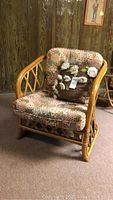 Front and side views of rattan chair with floral cushions and decorative appliqué pillow