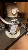 Front view of cream KitchenAid Ultra Power mixer with stainless steel bowl on shelf.