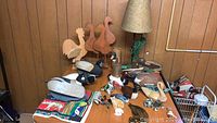 Full overview of all wooden, brass, and pottery duck and bird decor items on wooden table and floor.