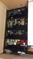 Metal shelving unit filled with various kitchen items from a frontal perspective.