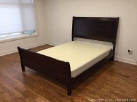 Perspective view of assembled queen bed with box spring on wood floor