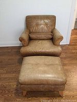 Front view of leather armchair with ottoman positioned in front