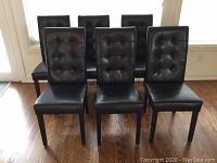 Six black tufted dining chairs arranged in two rows showing fronts