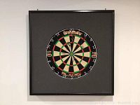 Front view of square backboard with mounted Winmau Blade 4 dartboard
