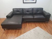 Front view of black leather chaise sectional showing three-seat sofa and left-facing chaise