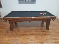 Full front view of table showing frame, legs and playing surface with balls racked at one end