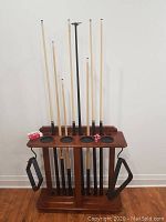 Front view of wooden rack stand holding eight cues and chalk on top surface