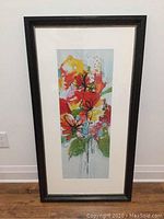 Full framed floral print leaning against a wall on wooden floor.