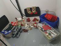 Wide view of all Christmas lights, stockings, ornaments in storage bins, figurines, wrapping paper in bins, and blue bin with fabric and tree topper.