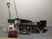 Full view of all tools including shovel, rake, handsaw, clamps, and several hand tools in trays and containers.