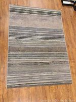 Full view of Stevens Omni area rug lying on wooden floor, shows striped pattern and size
