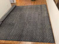 Full view of navy rug unrolled on wood floor
