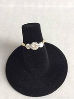 Front view of the ring on a black velvet display cone showing three diamonds.