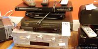 Stacked electronic devices: AV receiver, VHS player, Blu Ray player, DVD player, and remotes on top