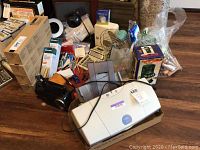 View of the lot contents including Canon printer, coin bank, fan, radio, alarm clock, and office supplies