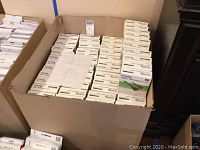 Wide view showing large quantity of boxed Plugable HDMI to VGA adapters stacked in a large box container.