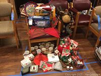 Full lot view showing moose figurine, Christmas mugs, trays, plates, and assorted fabric and decor items.