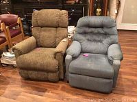 Two recliners, one brown fabric and one blue fabric, side by side on wooden floor, both with no visible damage