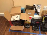 Photo of multiple boxed and unpacked electronic devices including antennas, players, and radios on floor