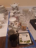 Image showing Evesham teapot, matching cups, poker-themed plates and mugs, multiple coffee mugs and cups arranged on a table
