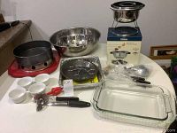 Photo showing all items including fondue set, mixing bowls, glass and metal baking dishes, ramekins, and utensils on a table.