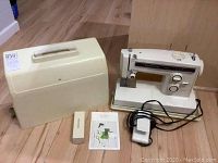 Full lot setup showing Kenmore sewing machine, carrying case, manual, and foot pedal on wood floor.