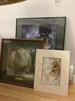 Three animal prints: unframed cougar print by Sue Coleman, framed wolf picture, and framed Robert Bateman print of lynx.