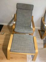 IKEA Poang armchair and ottoman with wood frames and light grey fabric upholstery shown from front with ottoman in foreground