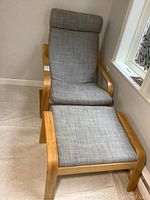 IKEA Poang armchair and ottoman in gray fabric and wood frame shown from front angle.