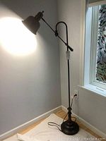 Full view of the floor lamp showing height, base, and adjustable arm with lampshade illuminating wall.