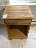 Front view of wooden night stand showing drawer and bottom shelf