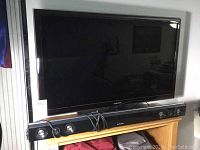Front view of Samsung 40-inch LED TV on stand with sound bar placed below on wooden surface