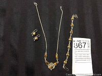 Full view of necklace, bracelet, and earrings laid out on black fabric showing the entire jewelry set