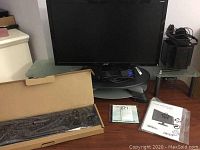 Acer LCD monitor with stand, black wired keyboard in box, and accessories on desk.