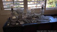Photo showing full assortment of clear cut glass items and the pair of vintage oil lamps with frosted glass globes on a black table.