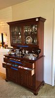 Full front view of wooden buffet and hutch showing glassware inside and drawers opened with blue painter's tape