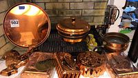 Copperware 5 pieces displayed on a fireplace ledge including a large round platter, a warmer with lid and stand, a pot, and several copper molds.