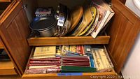 Photo of assorted metal pans, wooden cutting boards, and decorative platters inside a cabinet shelf