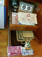 Drawer containing folded dish towels including Catstudio brand, and woven baskets below.