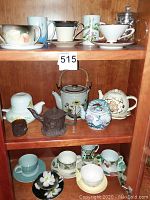 Full view of multiple teapots and teacups arranged on wooden shelves showing the variety and quantity of items