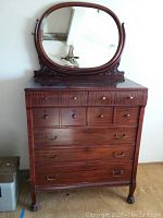Full view of dresser with attached oval mirror showing overall condition.