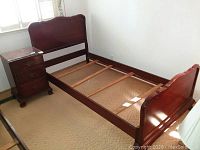 Full view of the twin bed frame with the nightstand placed next to it, showing the bed slats and wood finish.