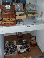Two shelves displaying multiple wooden and fabric-lined jewelry boxes and trays filled with assorted costume jewelry