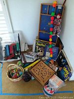 Wide view of the lot showing vintage board games including Twister, Alley Up, Stars, wooden peg board game, assorted miscellaneous game pieces, a hanging clown doll, and a basket with vintage toy balls.