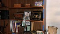 Wooden shelving displaying framed photos, decorative boxes, and books.
