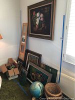 Wide shot showing seven framed artworks, box of playing cards, world globe and calendar replica