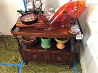 Pair of wooden end tables, one shown with decorative items on top and in open lower compartment.
