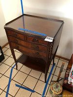 Full view of vintage small wooden cabinet showing overall shape, tapered legs, and lower shelf.