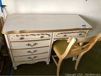 Full view of vintage desk with four drawers and chair tucked under desk.